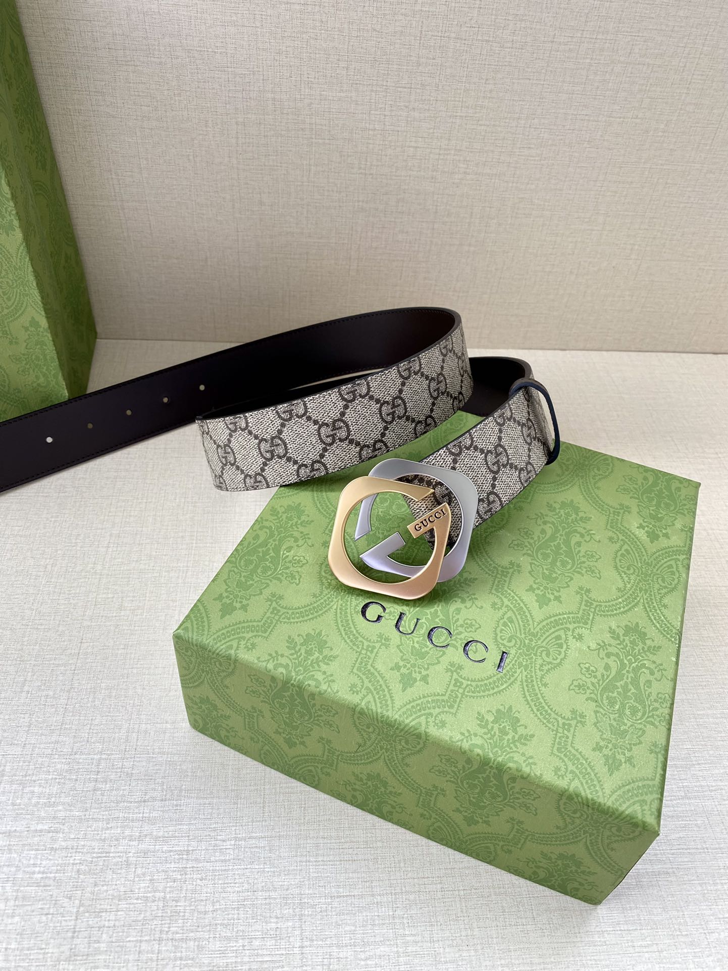 GG monogram belt with dark brown leather strap and gold-toned buckle beside gift box