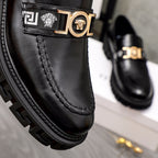 Black leather loafer upper with gold emblem buckle and geometric stitch details.