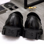 Black leather loafer heels with chunky lug soles, rear view pair.