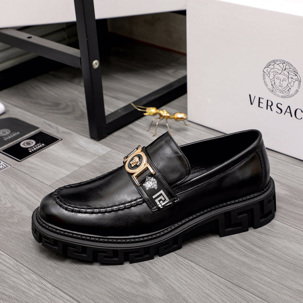 Black leather loafer with gold and black emblem bar detail and chunky platform sole.