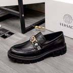 Black leather loafer with gold and black emblem bar detail and chunky platform sole.