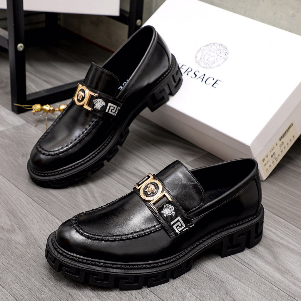 Black leather loafer pair with gold emblem buckle straps and textured lug sole.