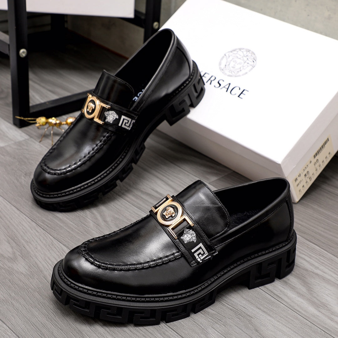 Black leather loafer pair with gold emblem buckle straps and textured lug sole.