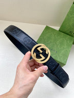 Gucci belt in dark navy with gold interlocking G buckle, held in hand