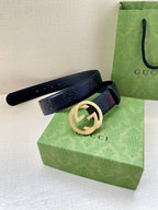Gucci belt in dark navy with gold interlocking G buckle, laid across box