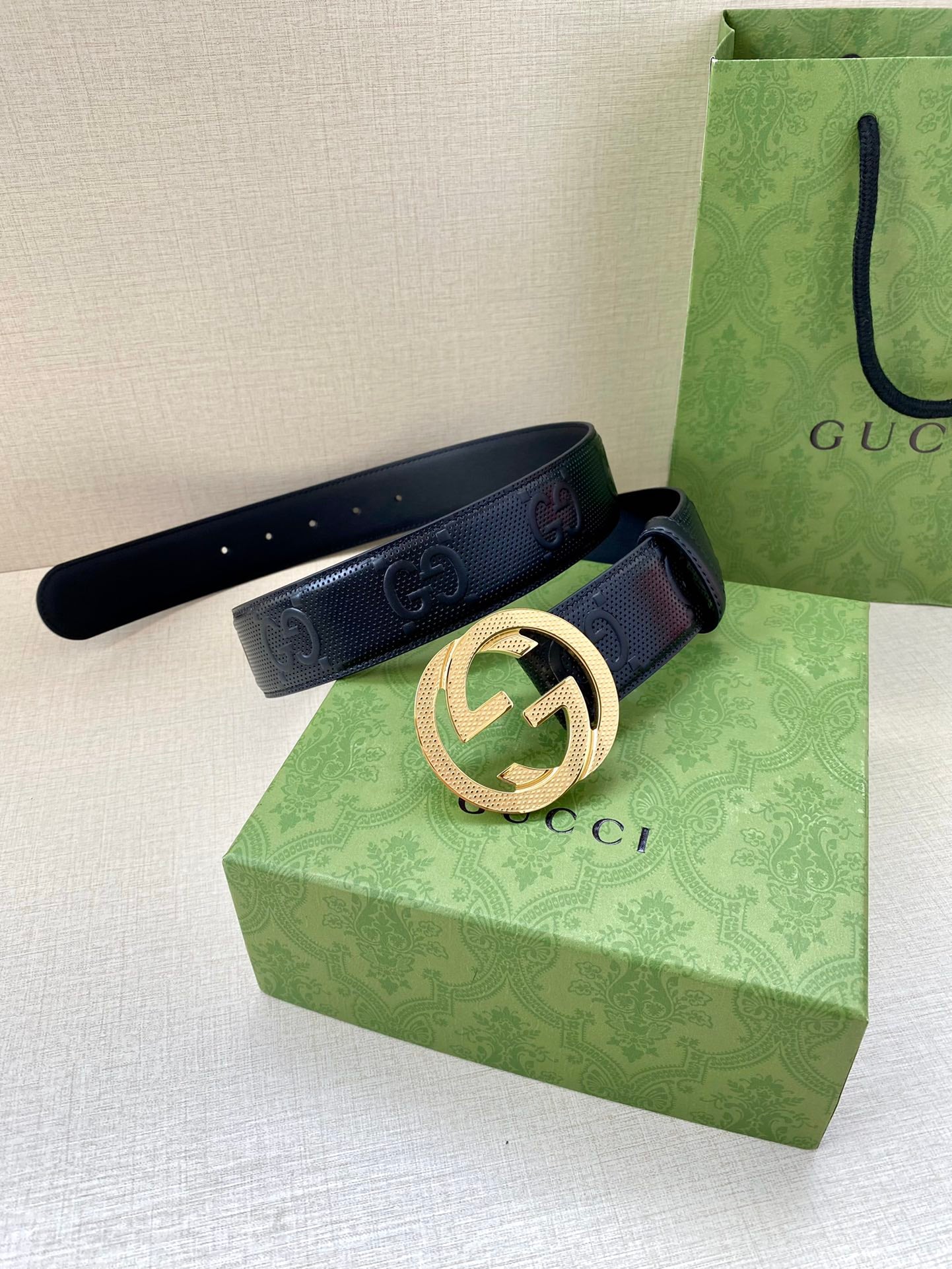 Gucci belt in dark navy with gold interlocking G buckle, laid across box