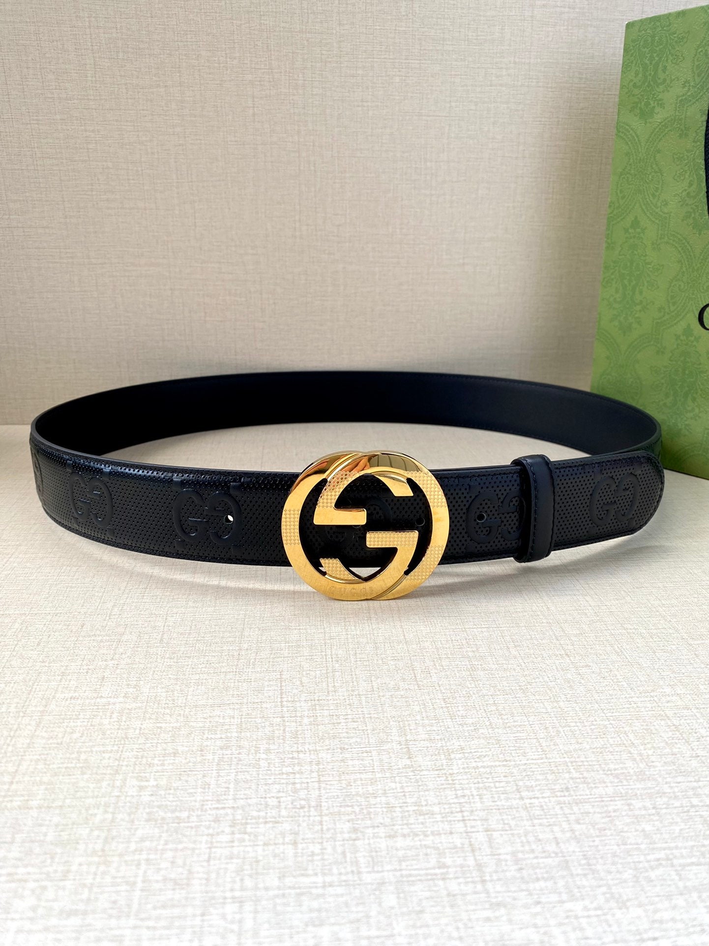Dark leather belt with embossed logo strap and gold-toned interlocking G buckle