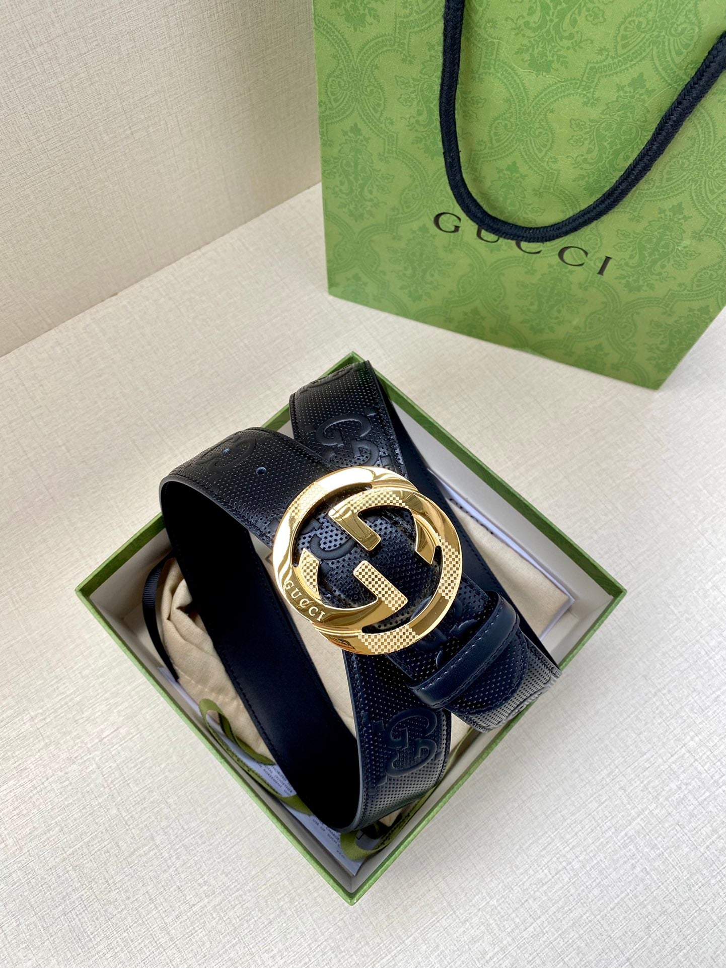 Navy leather Gucci belt with embossed monogram texture and gold-toned interlocking buckle