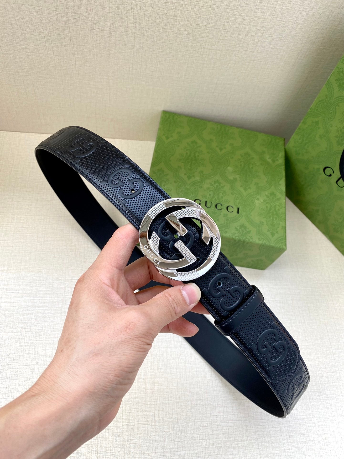 Navy leather Gucci belt with embossed logo pattern and silver-toned buckle