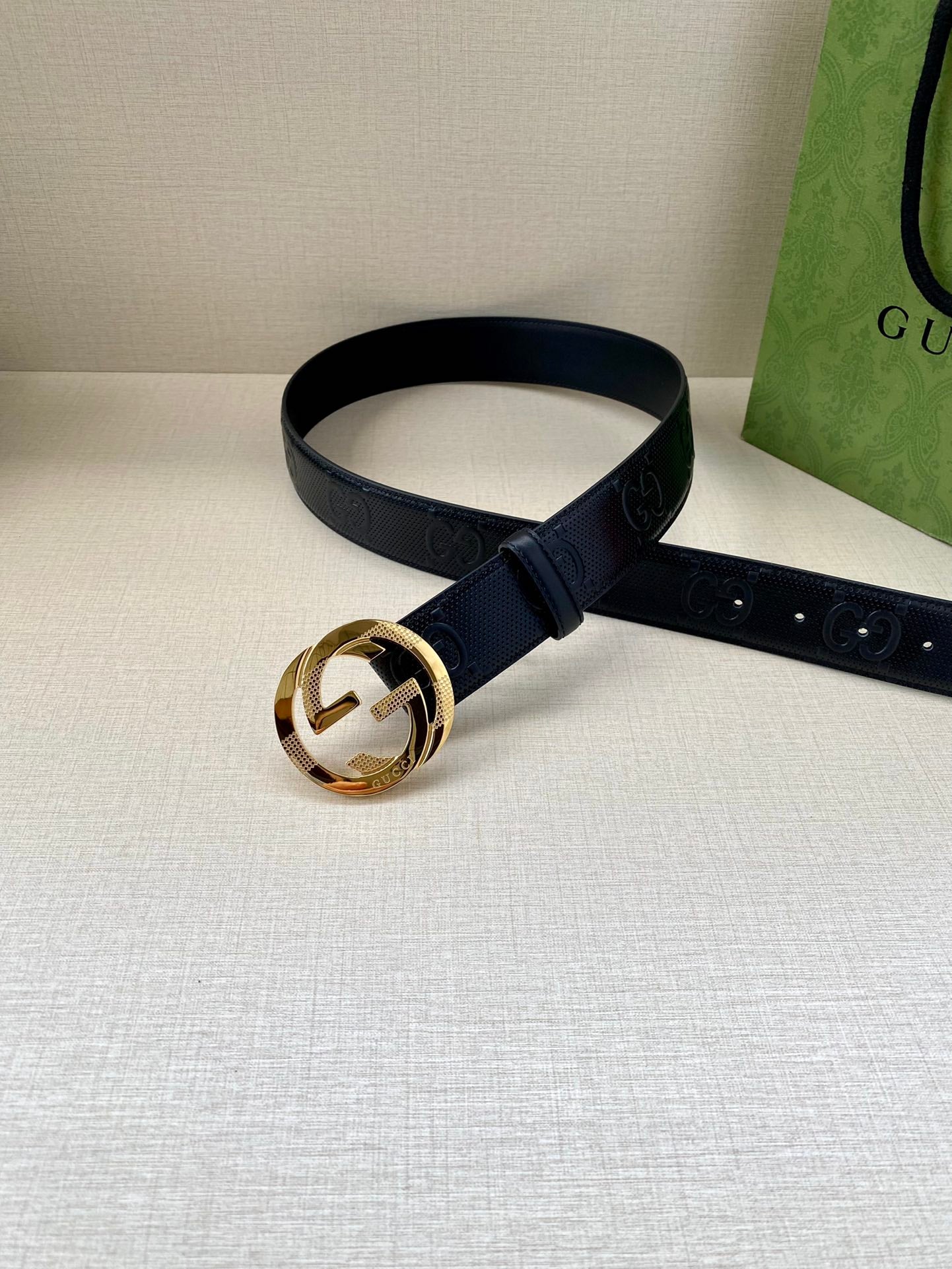 Navy leather belt with embossed logo strap and gold-toned round buckle