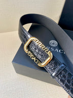 Crocodile-embossed leather belt close-up with gold-tone buckle and brand lettering