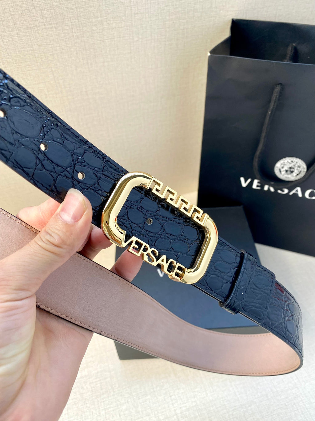 Designer belt with dark blue embossed leather and ornate gold buckle clasp