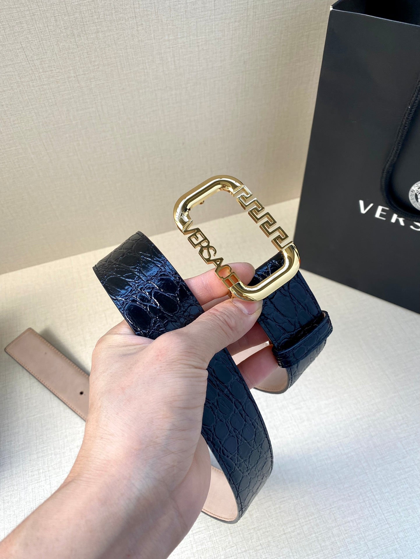 Designer belt with dark blue embossed leather and ornate gold buckle