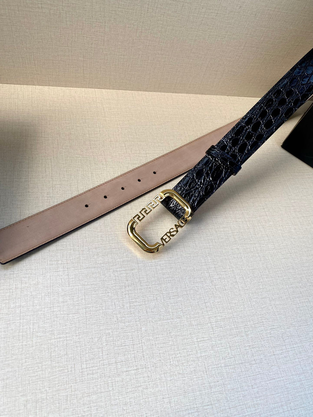 Designer belt with dark blue embossed leather strap and gold oval buckle