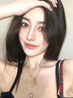 Gold cross pendant necklace worn by person with black top