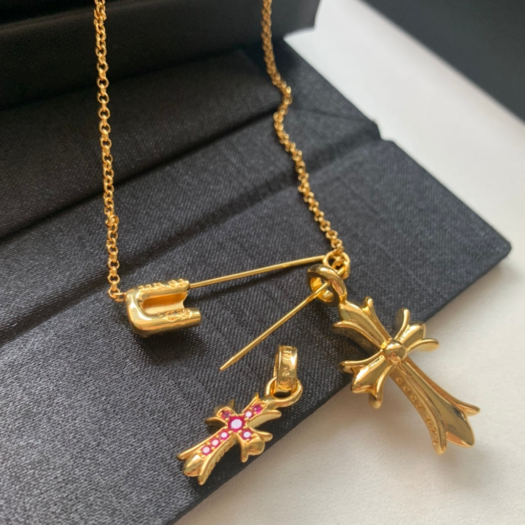 Gold chain necklace with cross pendants and pink gemstone accents, bar clasp
