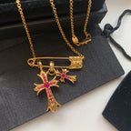 Gold cross pendant necklace with pink gemstone inlay and bar clasp