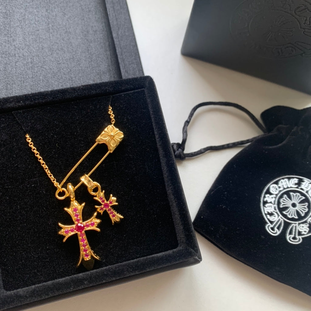 Gold cross pendant necklace with pink gemstone accents in a black gift box