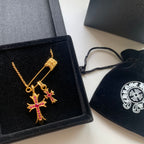 Gold cross pendant necklace with pink gemstone accents in a black gift box