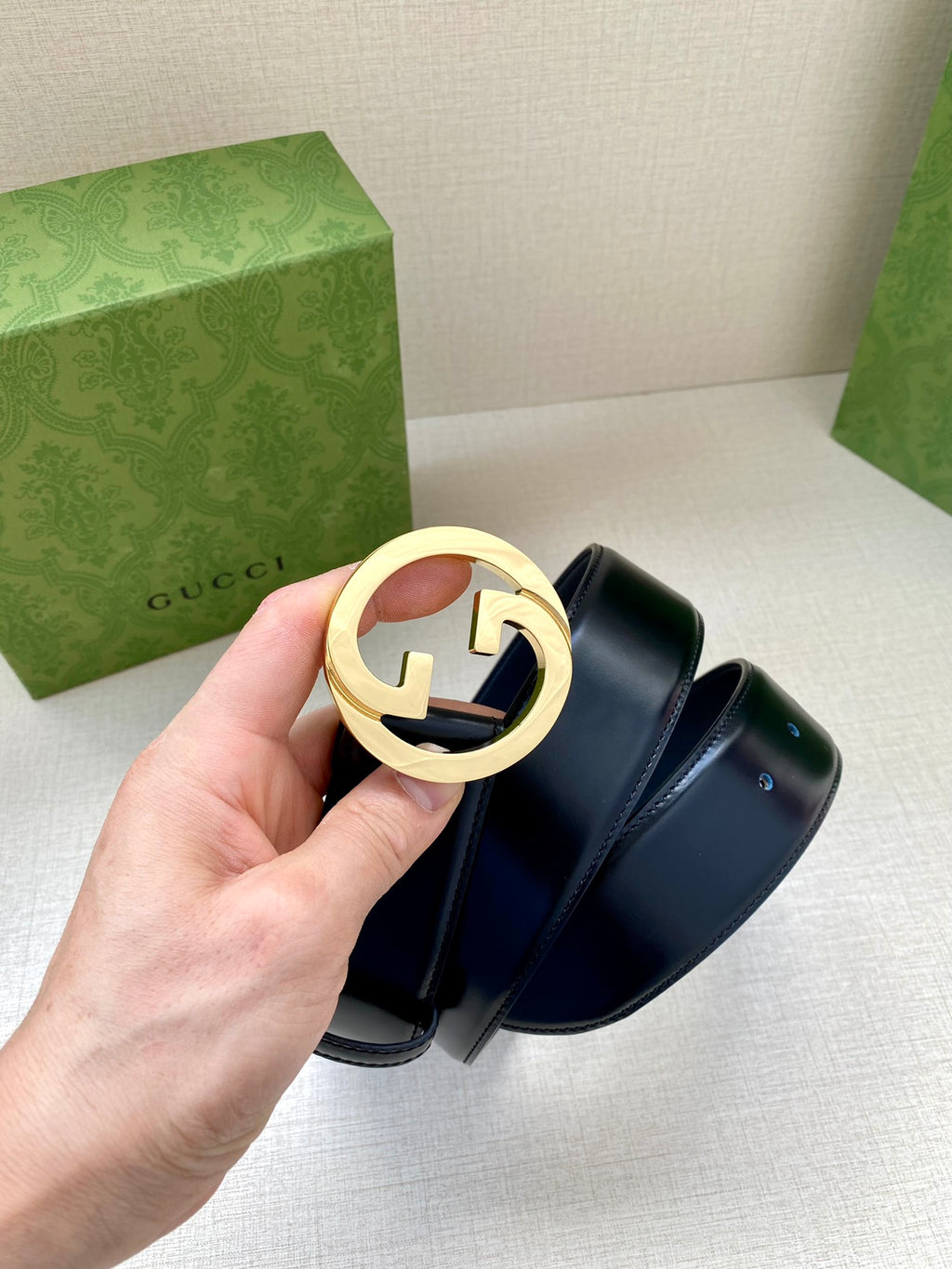 Gucci belt, dark blue leather belt with gold-tone G buckle in hand