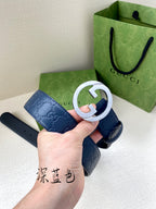 Gucci belt close-up: dark blue strap with white-ring G buckle, held up