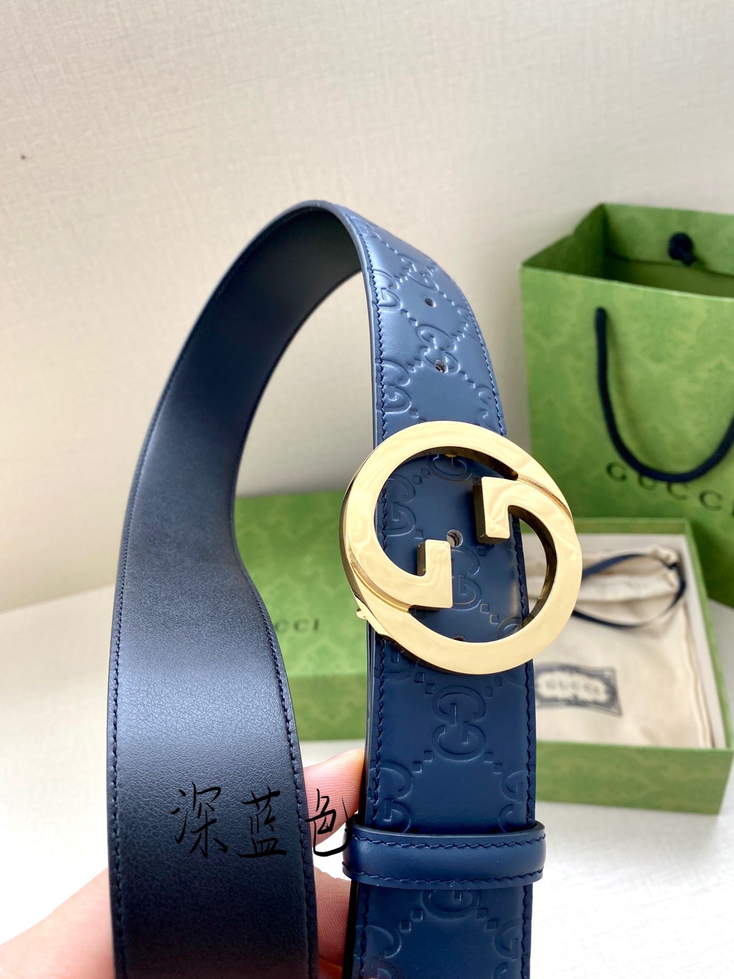 Gucci belt detail: dark blue strap with G buckle and gold center