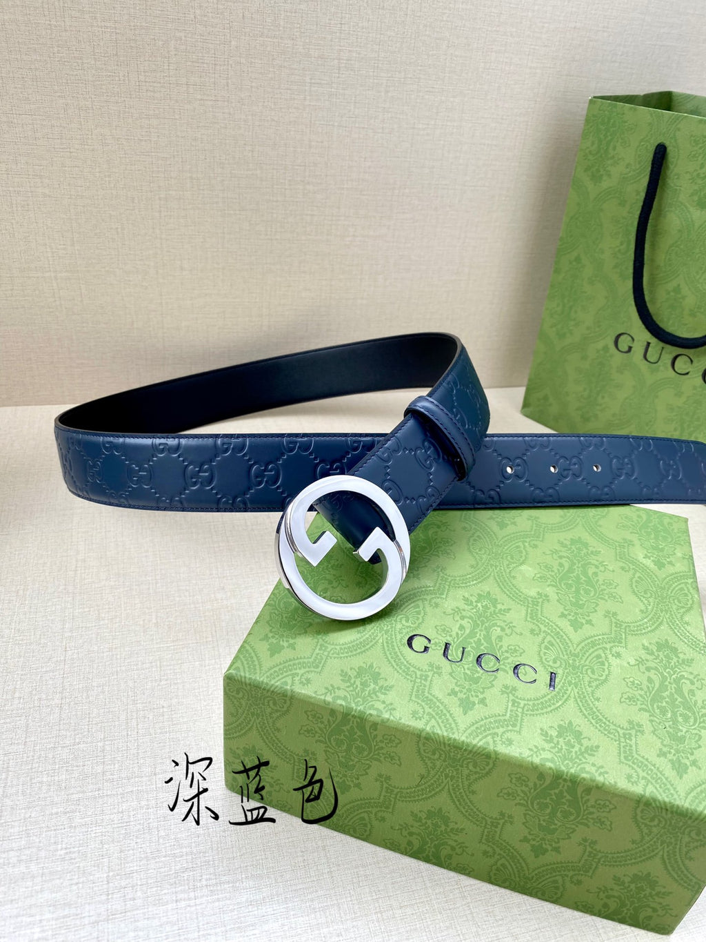 Gucci belt front view: dark blue embossed strap with white-ring G buckle