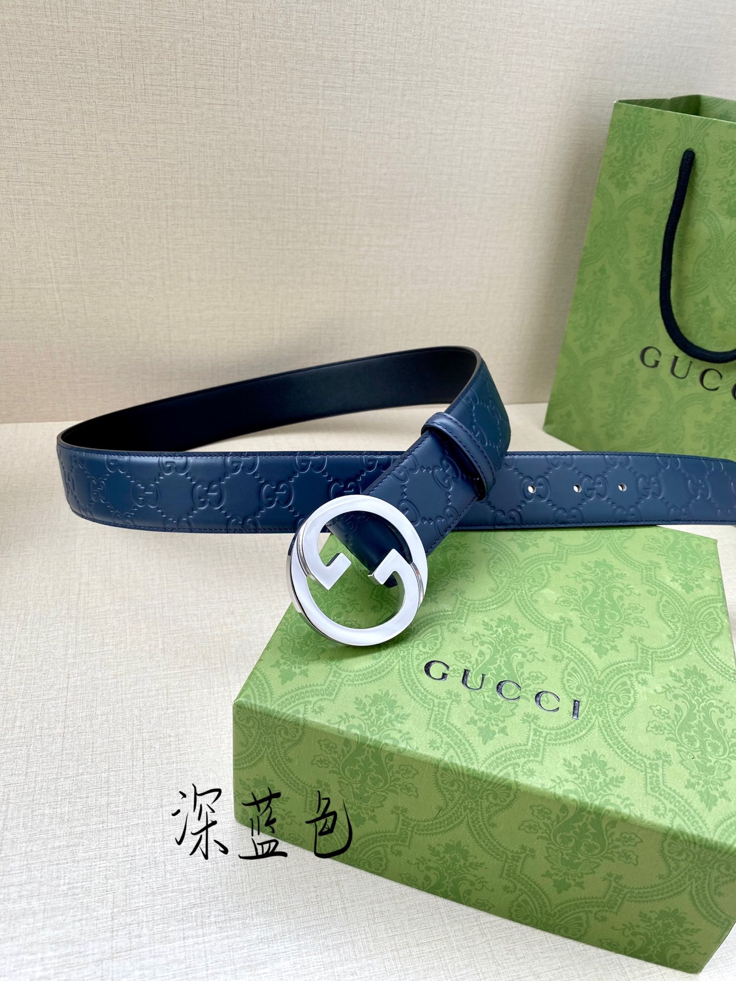 Gucci belt front view: dark blue embossed strap with white-ring G buckle