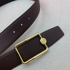 Embossed leather belt with rectangular gold buckle, dark brown strap close-up.