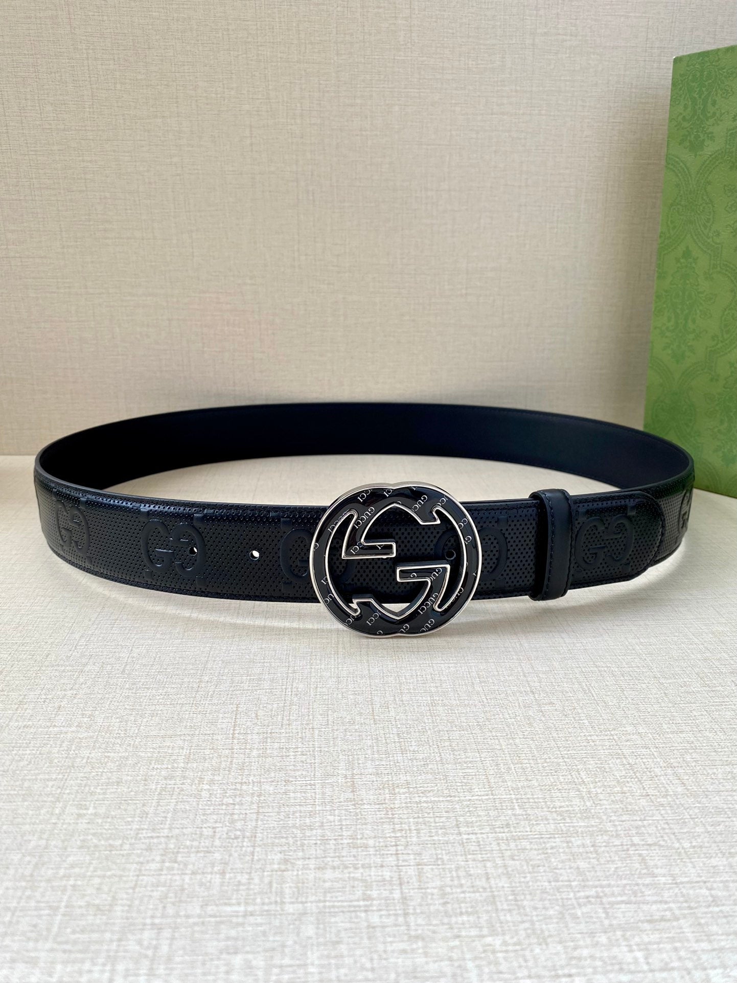 Gucci dark navy leather belt on display with oval GG buckle and strap texture