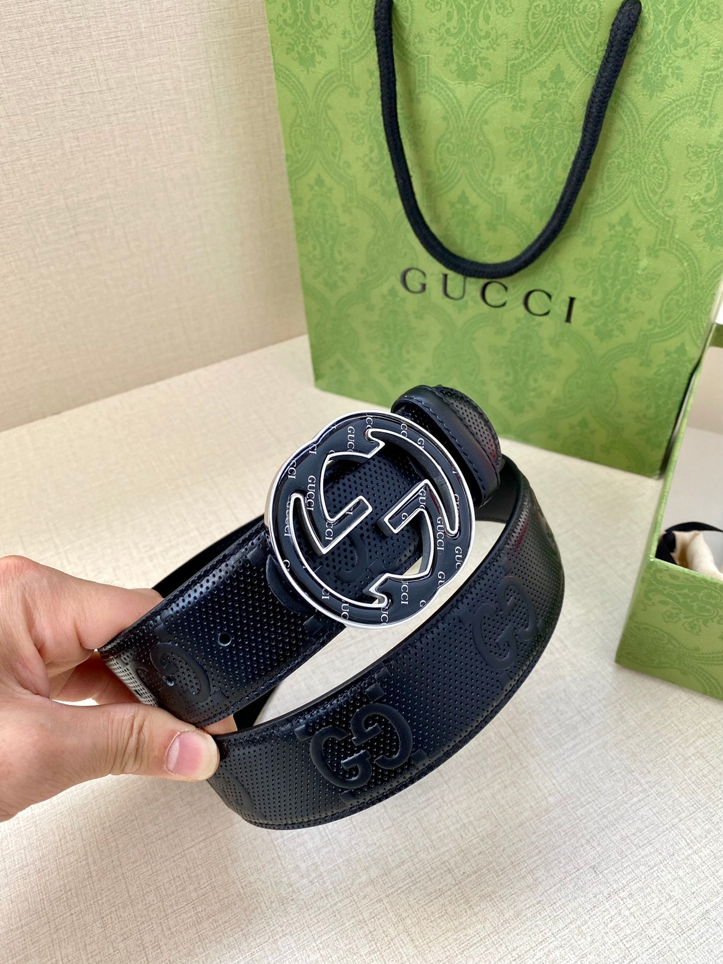 Gucci dark navy leather belt close-up on GG buckle with metal edge trim