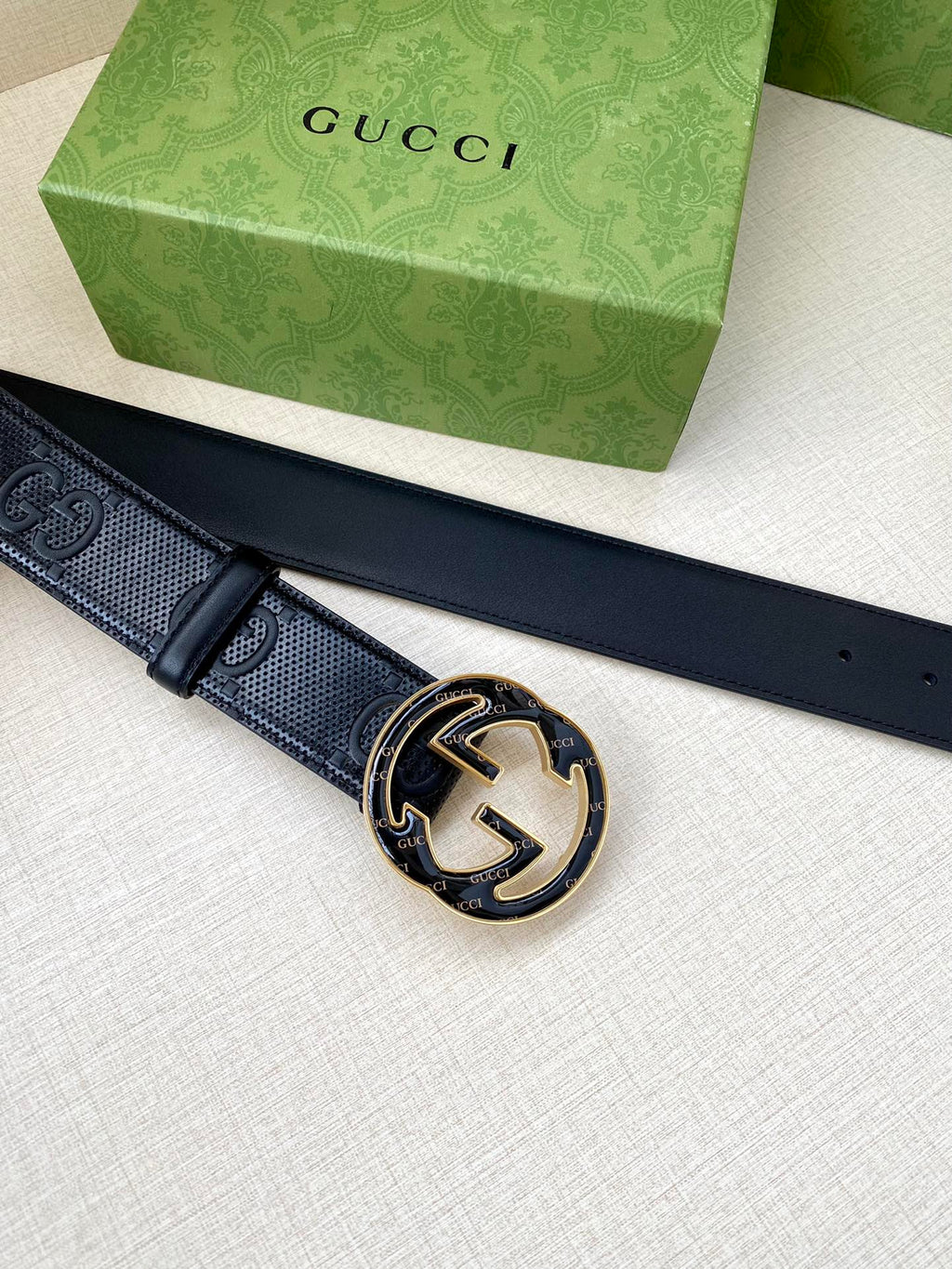 Gucci dark navy belt lying flat with round GG buckle and stud holes