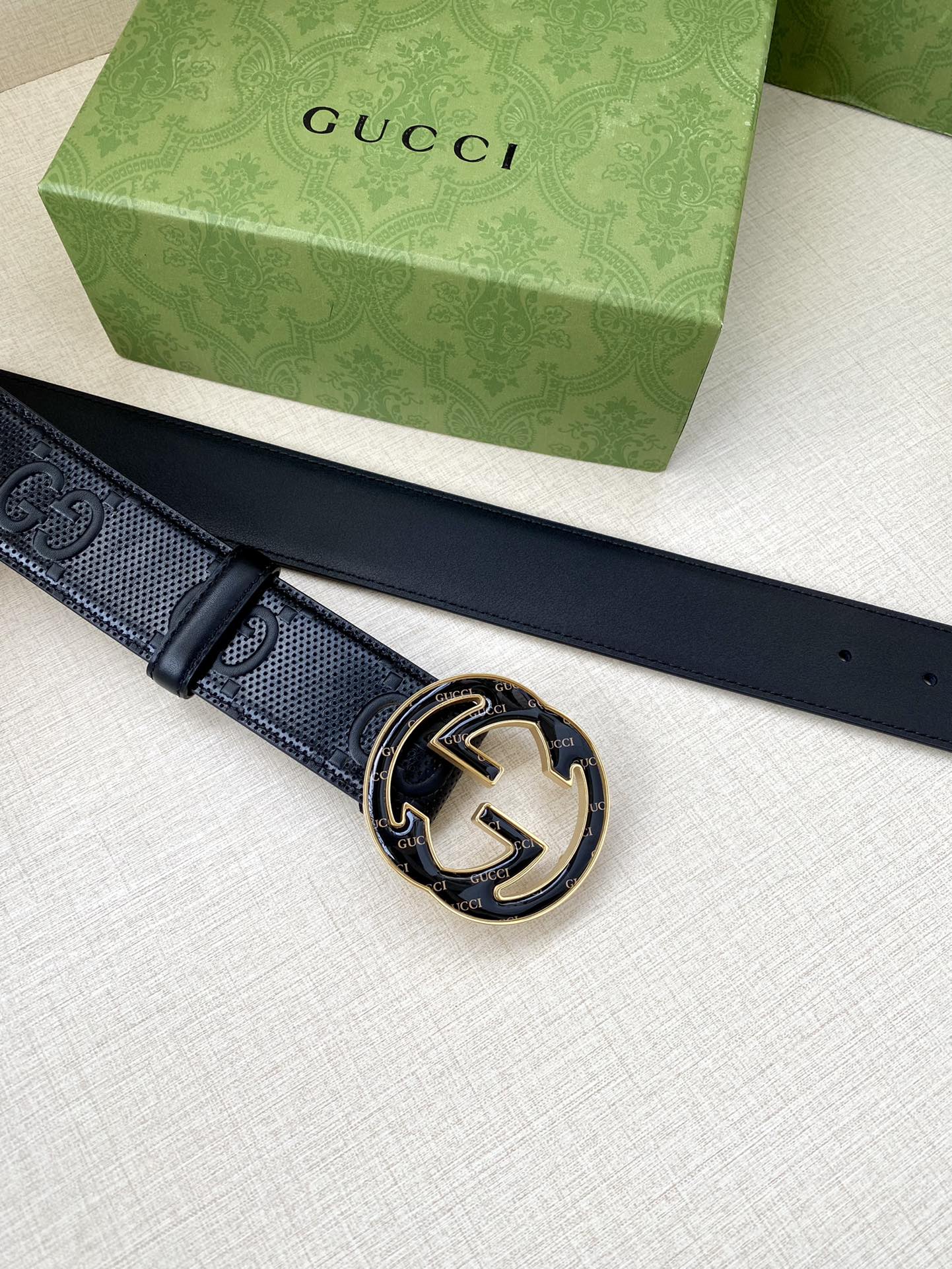 Gucci dark navy belt lying flat with round GG buckle and stud holes
