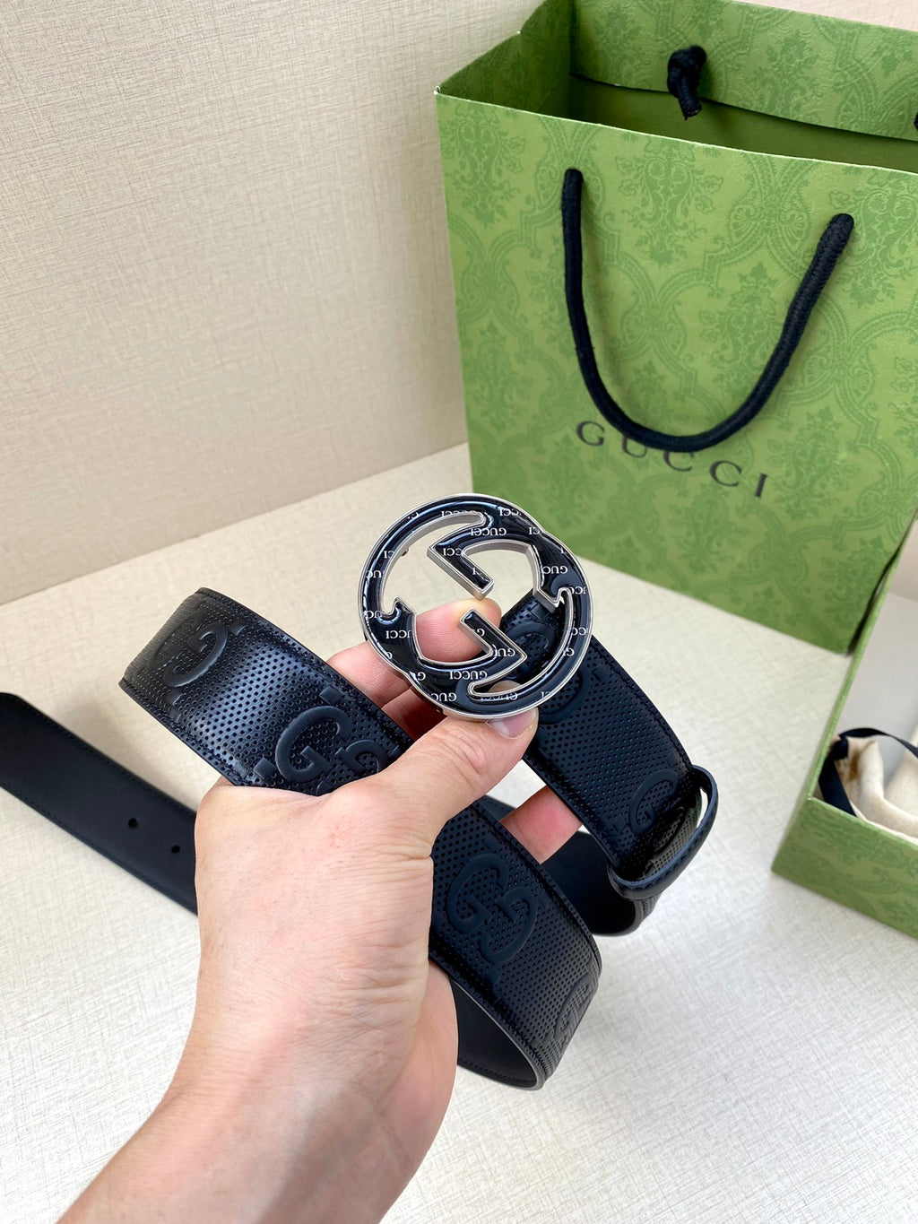 Gucci dark navy belt showing front buckle and perforated GG strap detail
