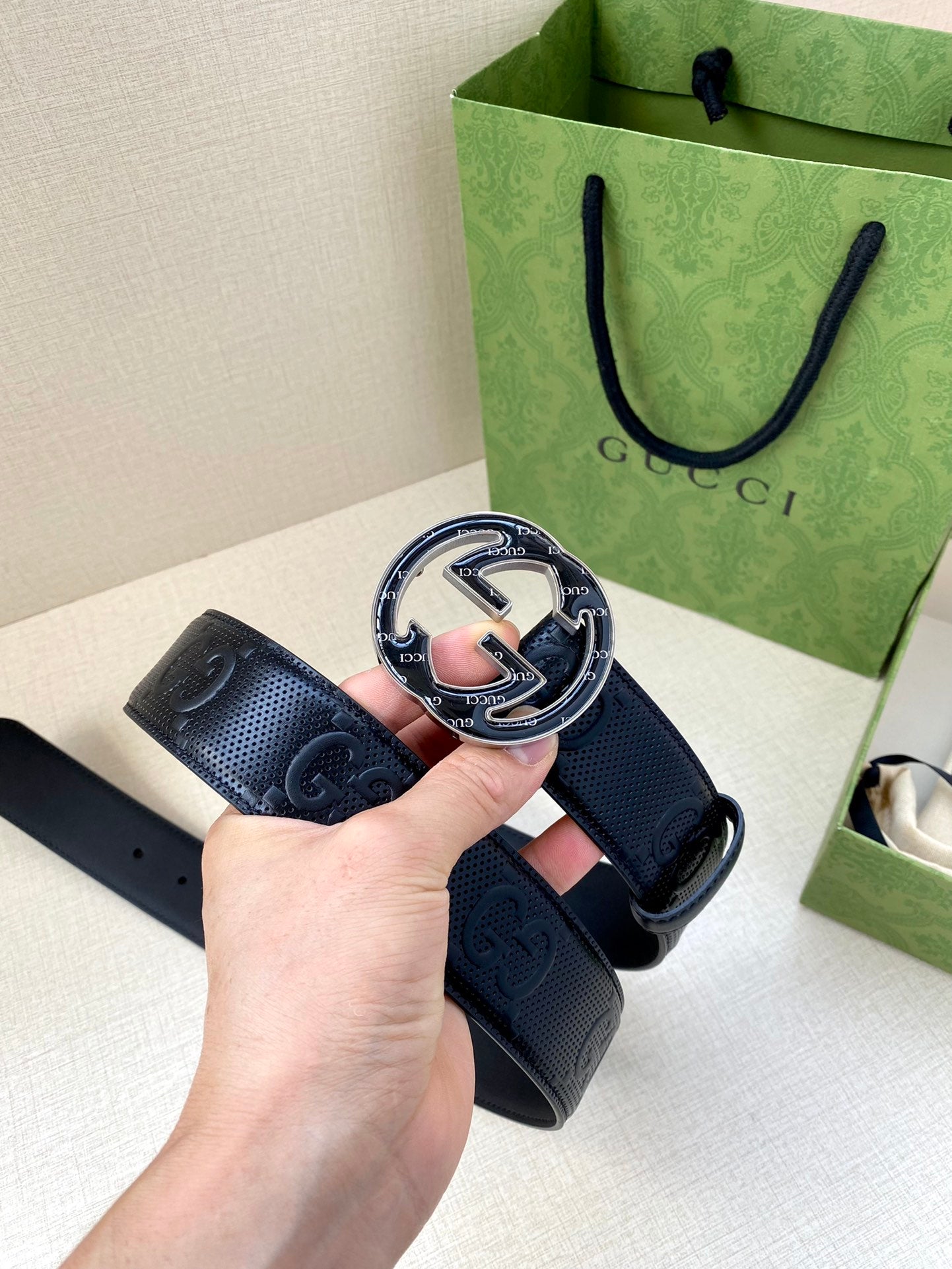 Gucci dark navy belt showing front buckle and perforated GG strap detail