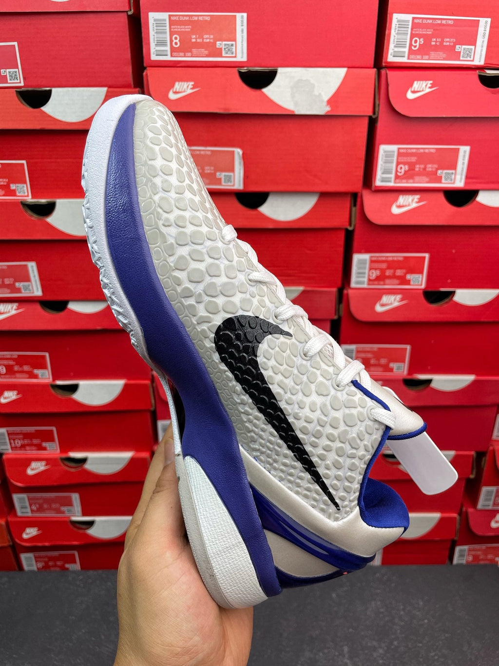 White and blue basketball sneaker, side view showing textured upper and black stripe.