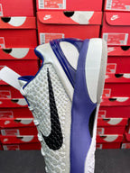 White and blue basketball sneaker, rear side view with textured upper and black stripe.