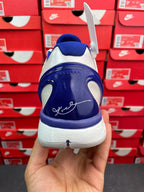 Blue and white basketball sneaker heel view with swoosh graphic and lace tag.