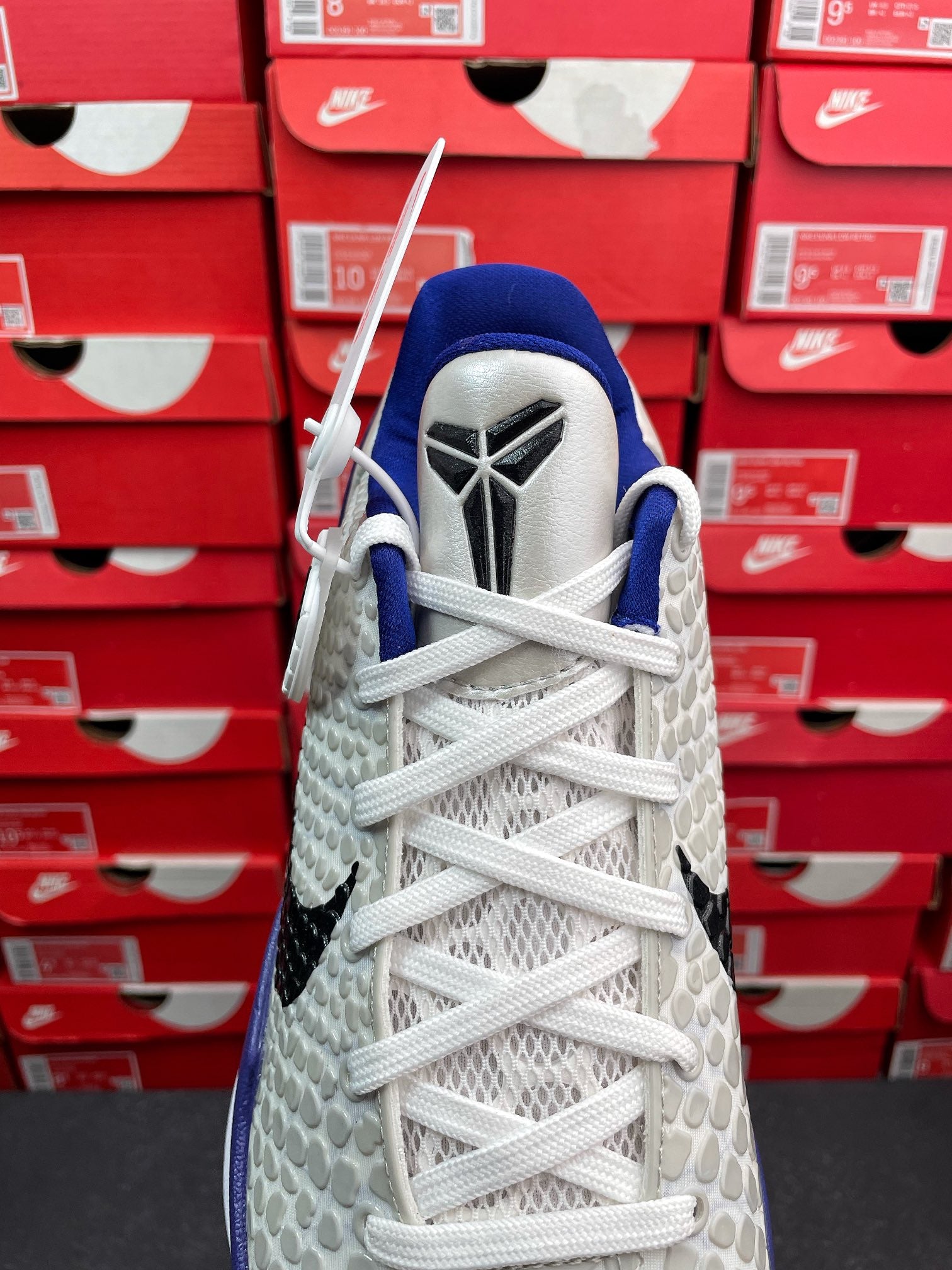 White basketball sneaker with blue collar and woven laces, top view with tongue label.
