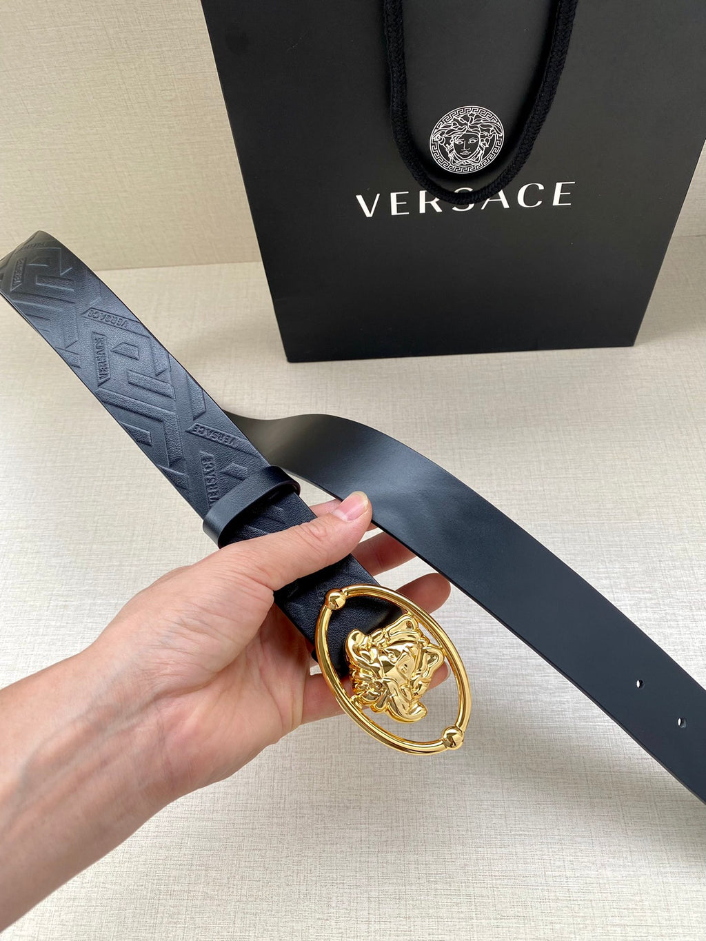 Versace belt close-up, dark blue embossed leather with gold-tone lion buckle