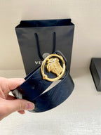 Versace belt held in hand, dark blue embossed leather with gold-tone oval buckle