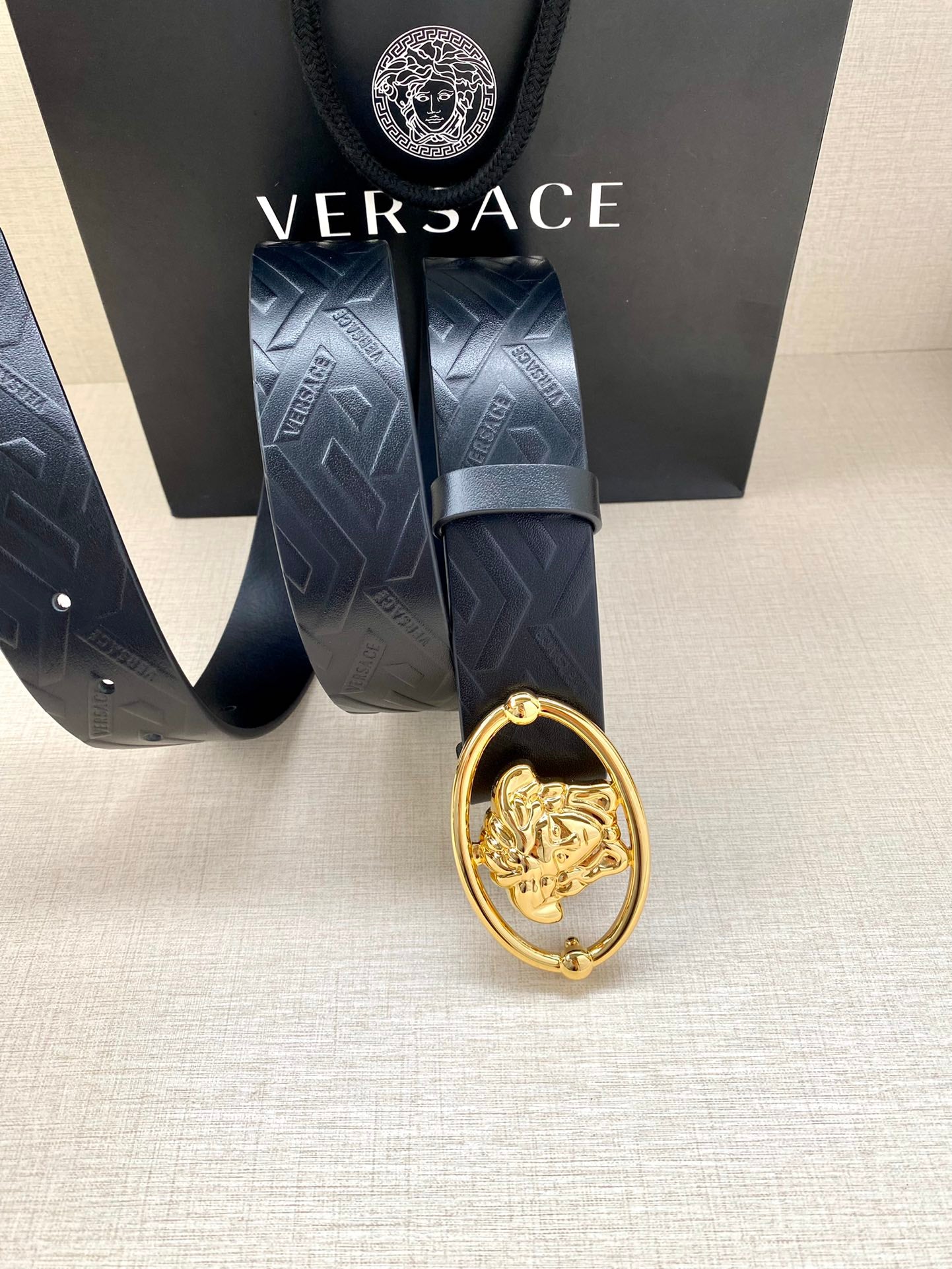 Versace belt detail, dark blue embossed strap with gold-tone lion crest buckle