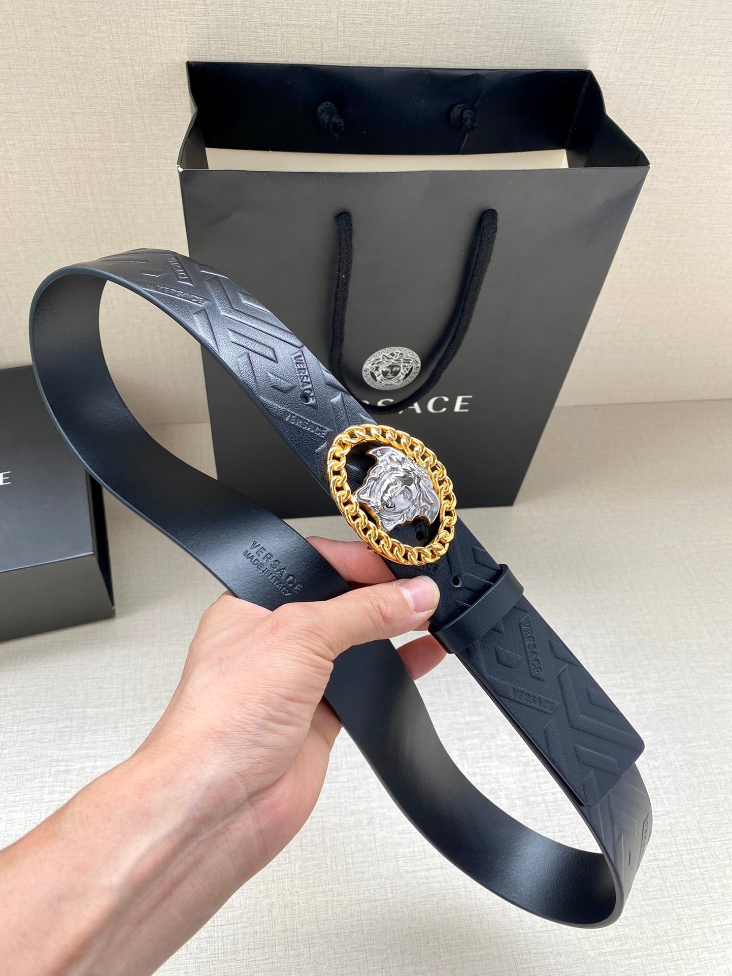 Black belt with embossed pattern and gold Medusa oval buckle