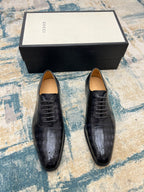 Pair of black leather lace-up dress shoes with perforated toe