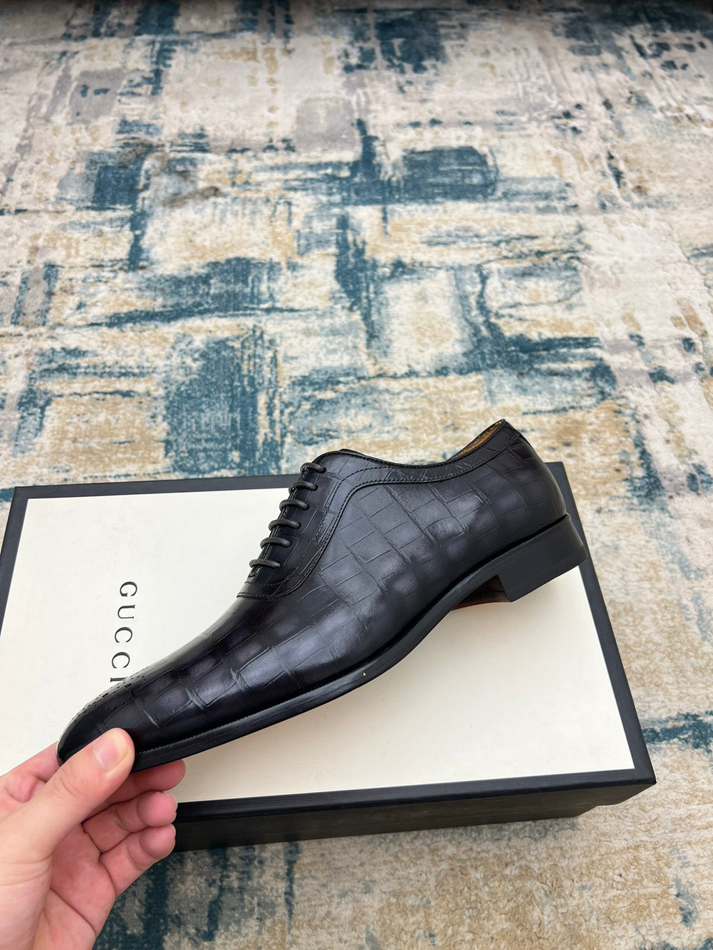 Black leather lace-up dress shoe with wingtip perforations, single shoe