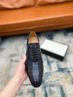 Black leather lace-up dress shoe held up, perforated toe