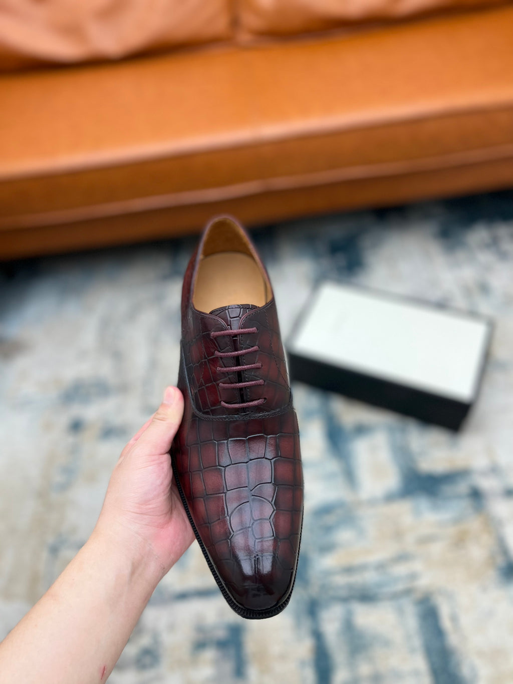 Single lace-up dress shoe, burgundy croc-textured leather with laces, held up.