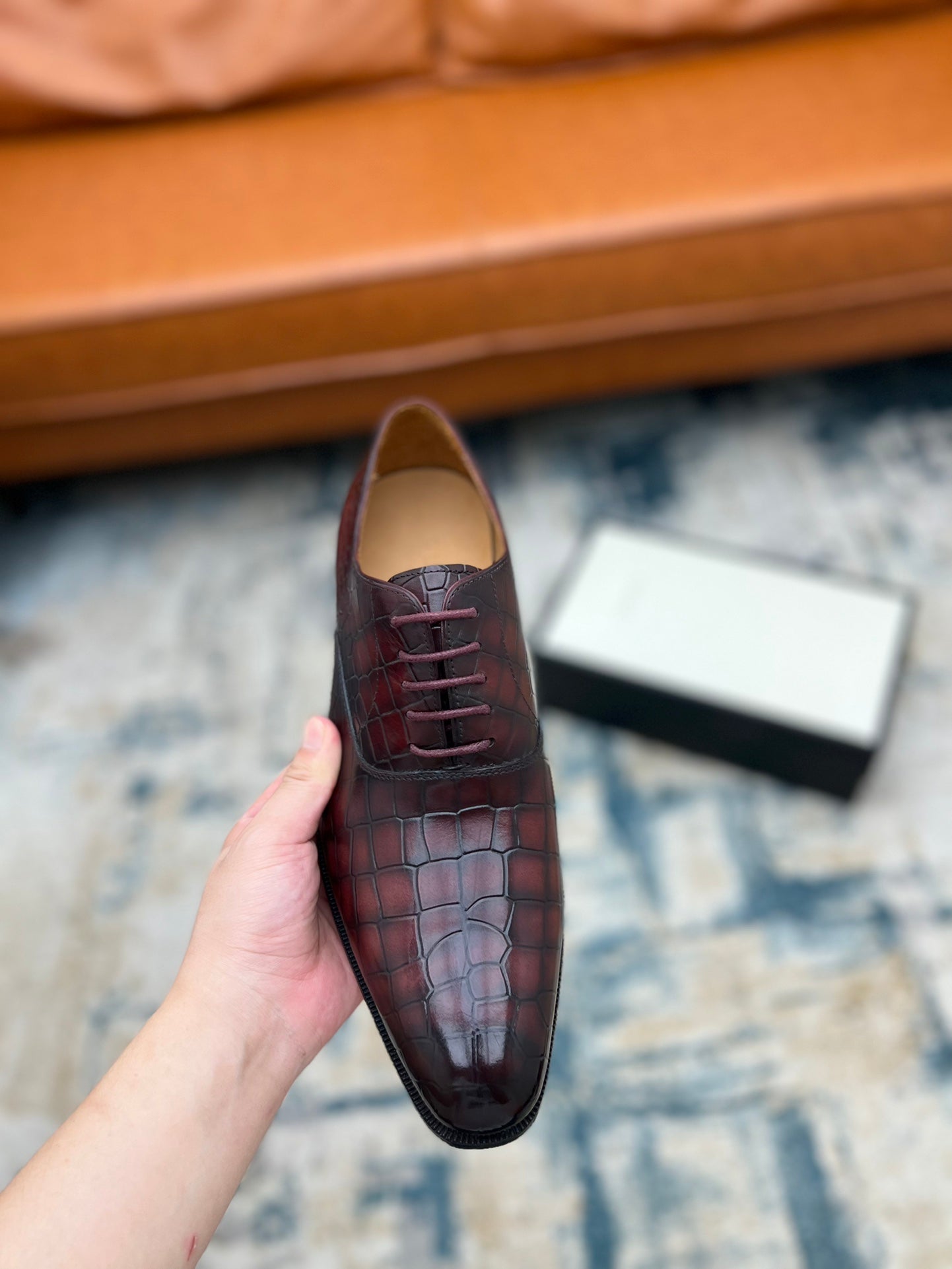 Single lace-up dress shoe, burgundy croc-textured leather with laces, held up.