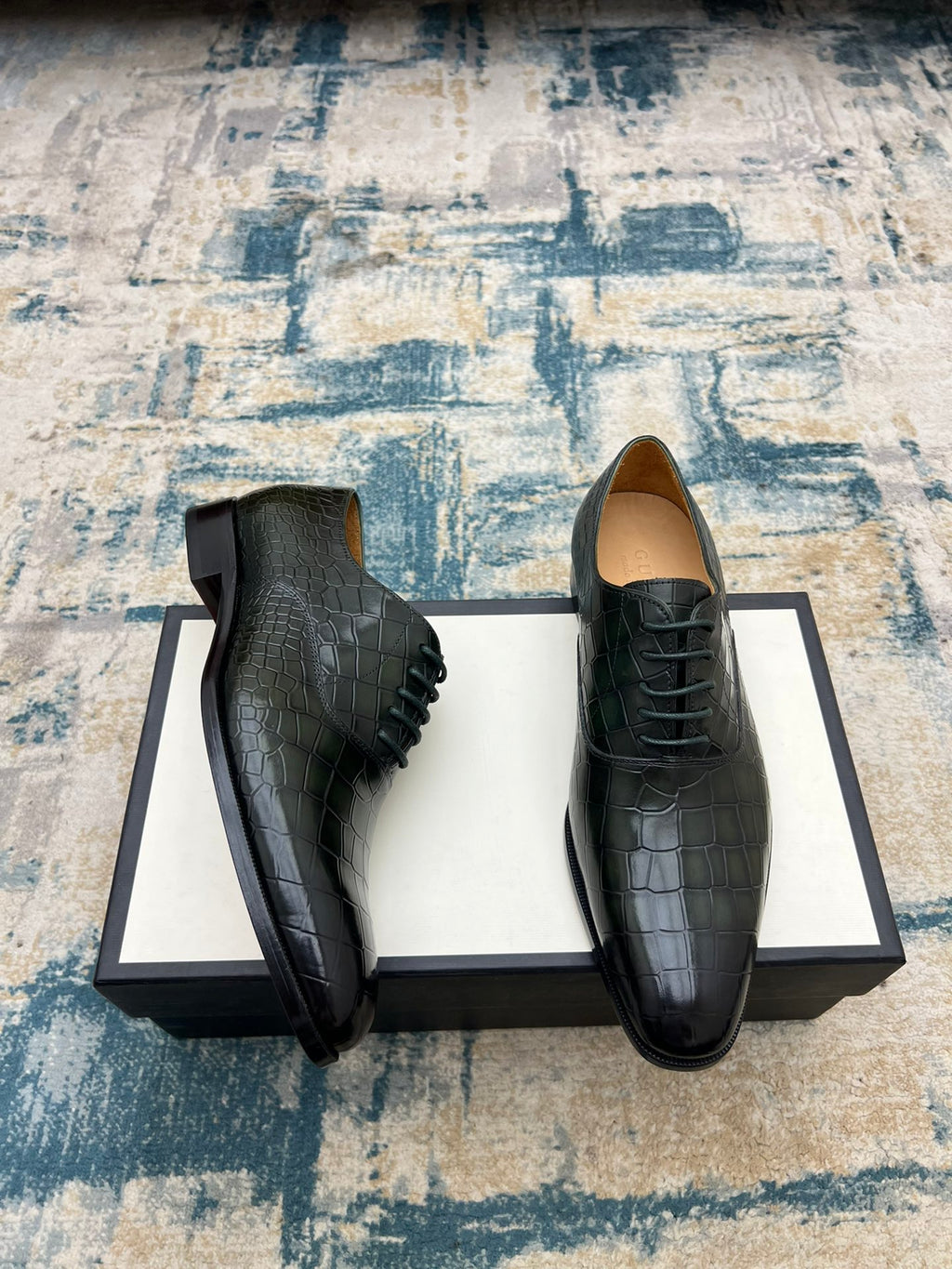 Black crocodile-embossed lace-up dress shoes, side view pair on box