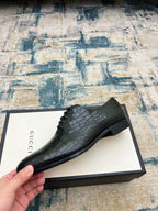Black crocodile-embossed lace-up dress shoe on branded box, side angle